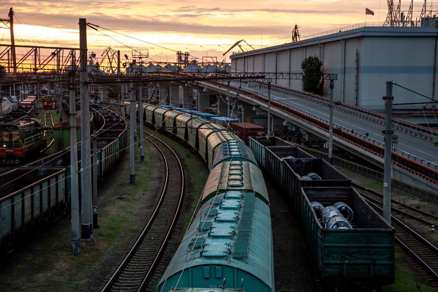 Logistikstandort in K&auml;rnten mit Bahnanschluss und G&uuml;terz&uuml;gen bei Sonnenuntergang